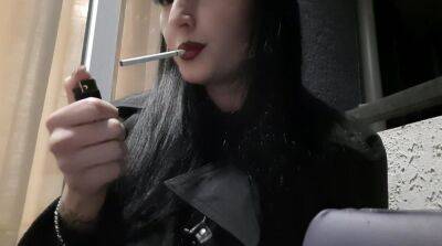 Dominatrix Nika smokes a cigarette on the balcony. Mistress sexy red lips blow smoke in your face - sunporno.com